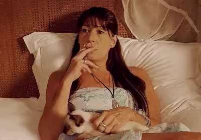 Woman smoking on bed and cat in arms
