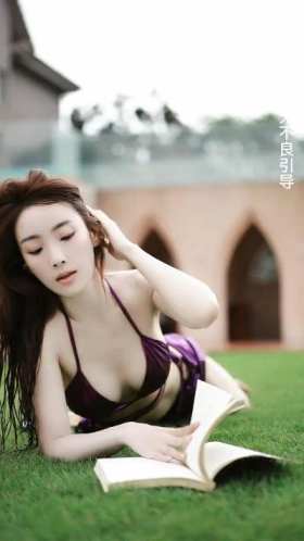 Chinese female host Ma Hui, wearing a swimsuit, lying on the lawn and reading a book short MP4 video