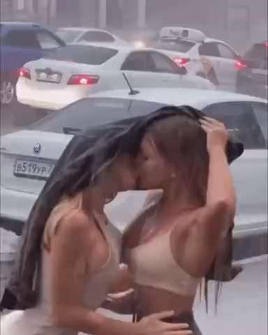 Two girls kissing passionately in the heavy rain