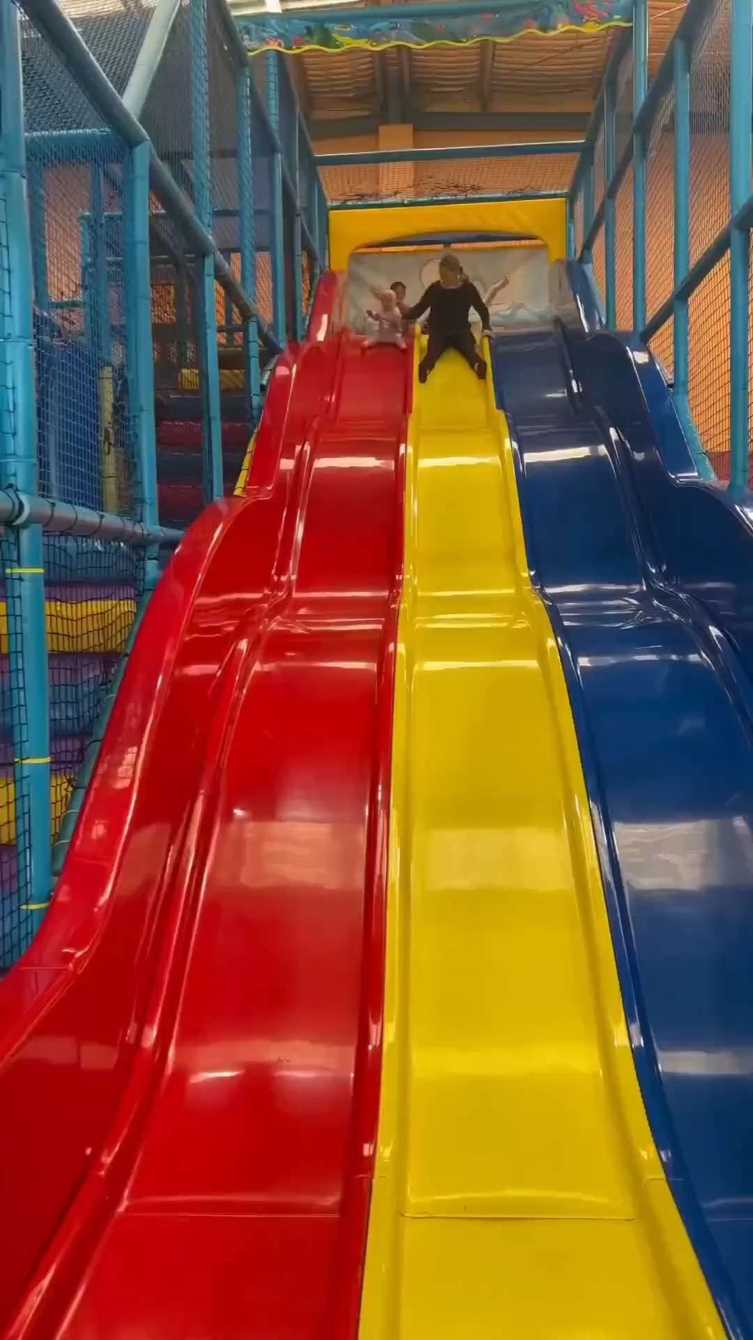 Little girl riding the slide with her toy doll