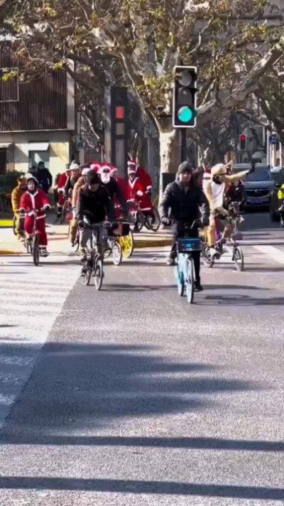Shanghai, people are dressed as Santa Claus to ride a bicycle to celebrate Christmas